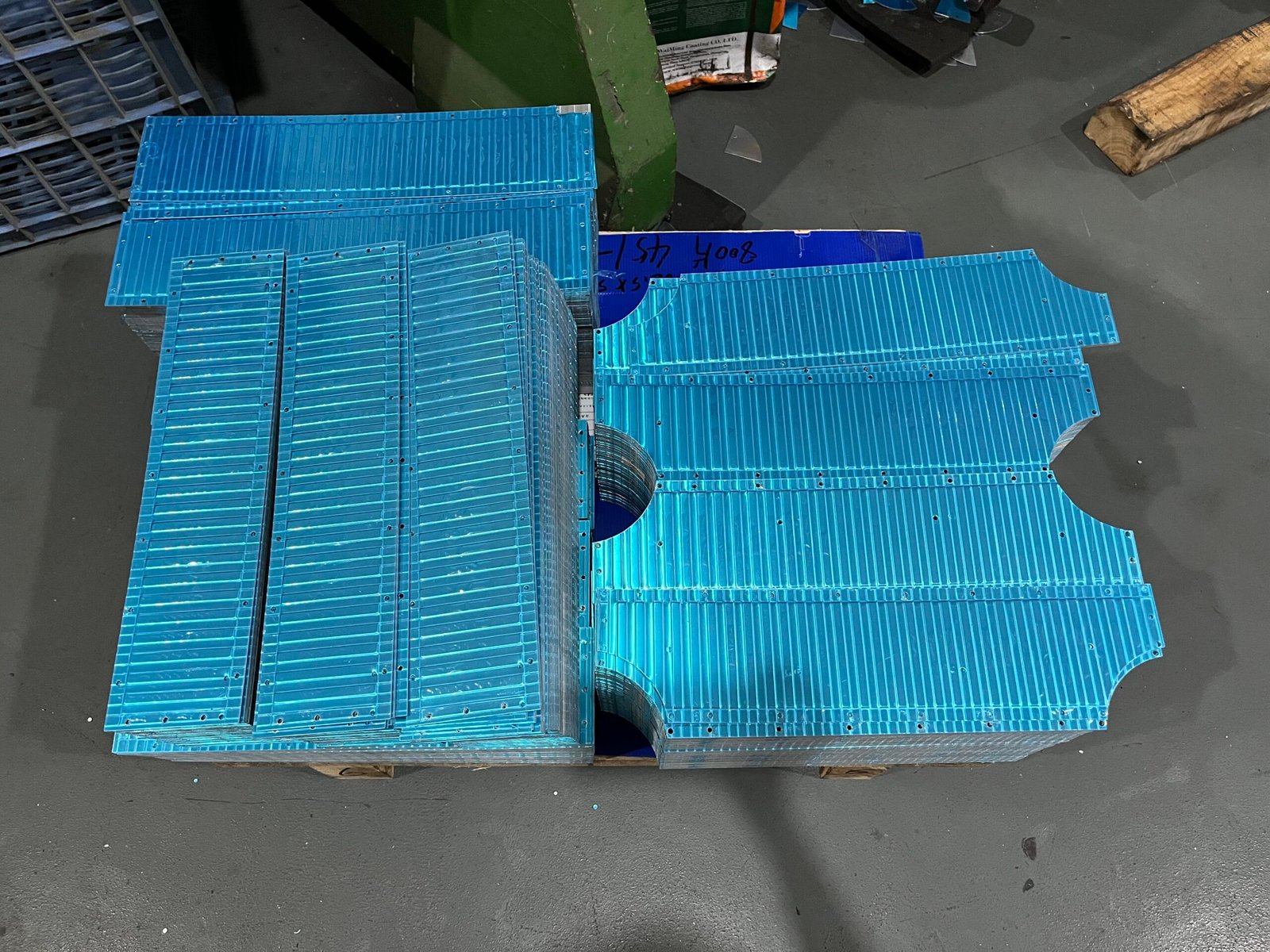 Stacks of ribbed aluminum luggage panels with cutouts and mounting holes