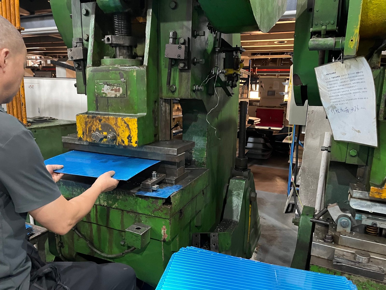 Worker positioning a ribbed aluminum panel at a press