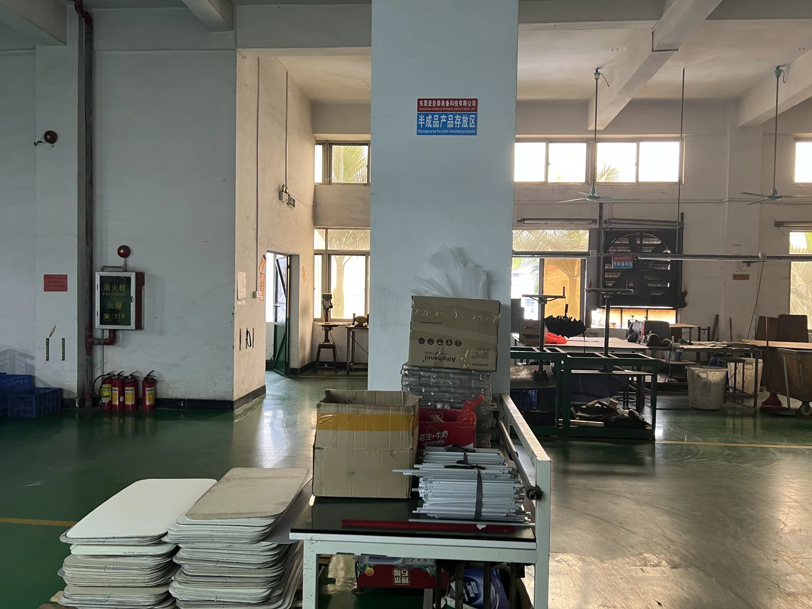 Semi finished goods storage area with stacked white panels on a trolley and cartons of components
