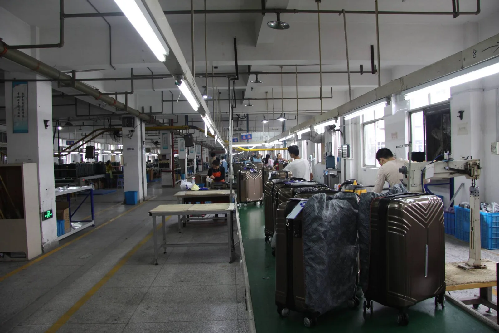 Production hall with finished luggage in protective covers staged toward the inspection area