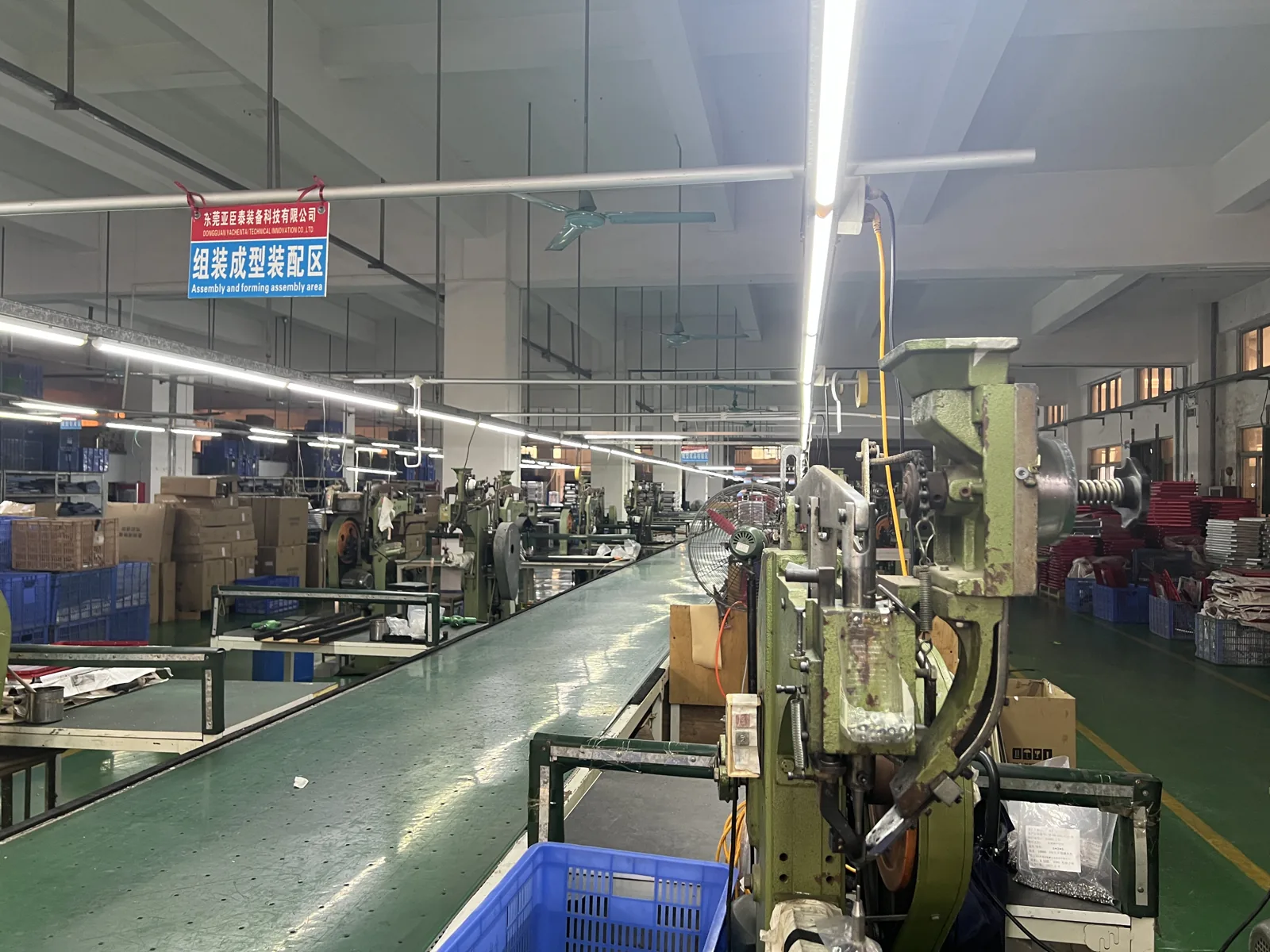 Assembly and forming area with riveting presses along a conveyor and crates of components alongside