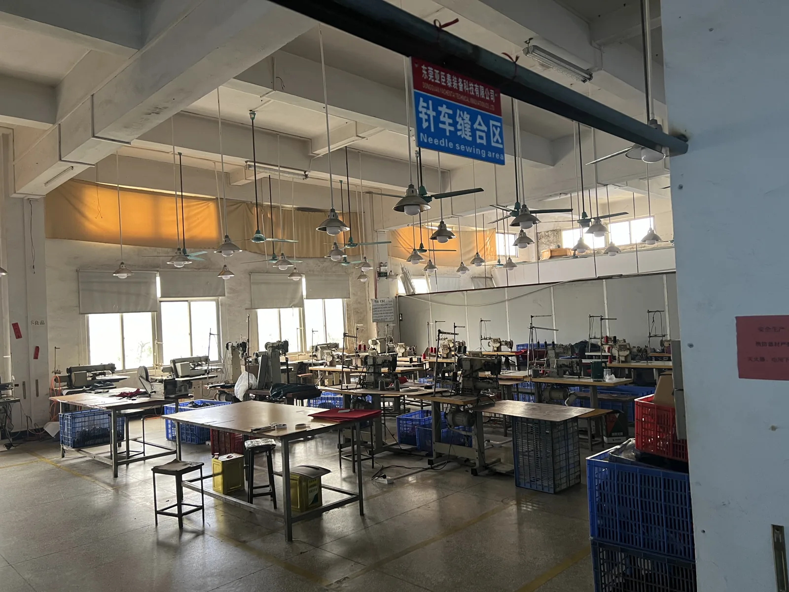 Wide view of the needle sewing area with rows of industrial sewing machines and parts crates