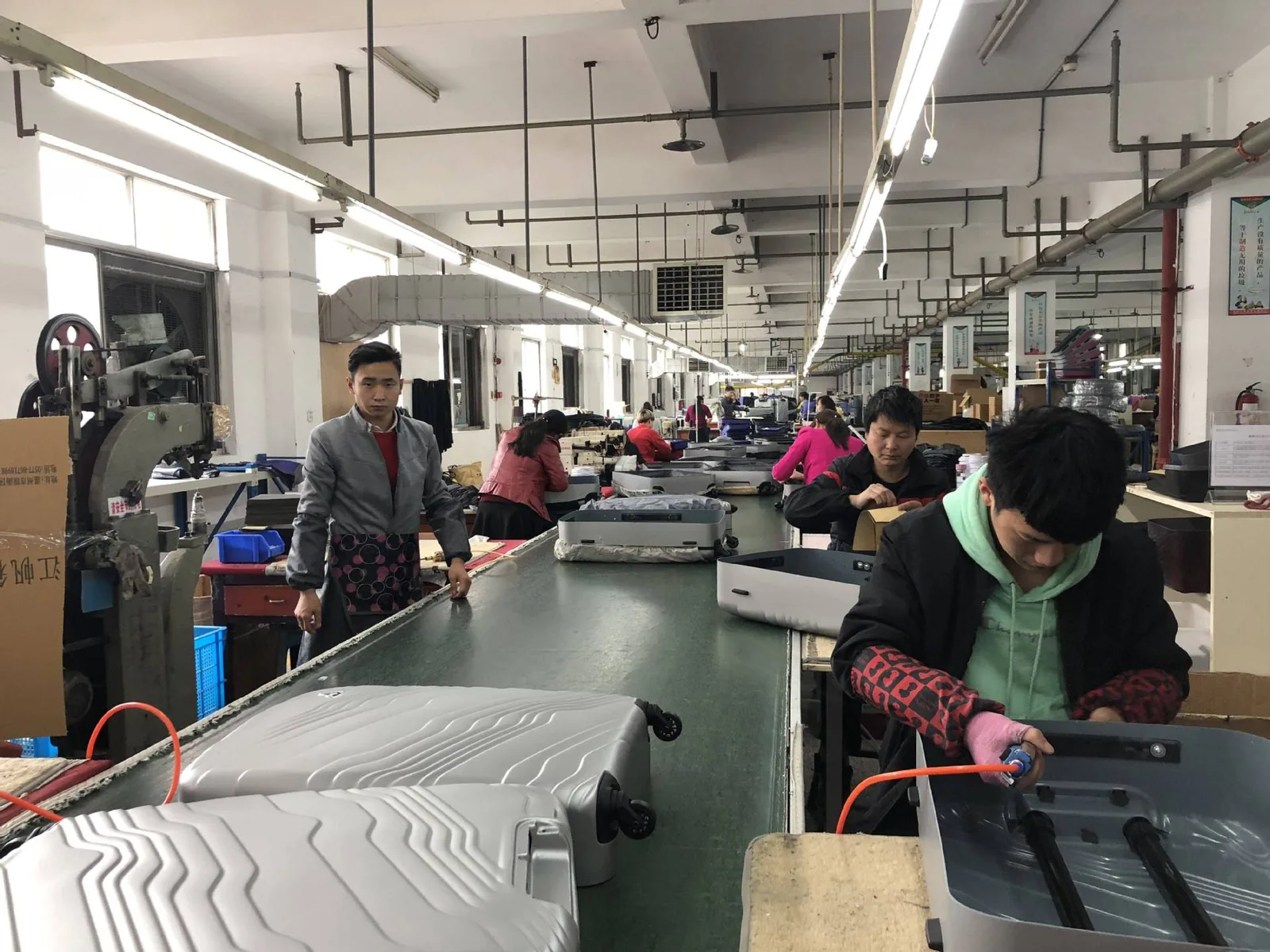 Assembly conveyor where luggage shells are fitted with handles, wheels, and interiors