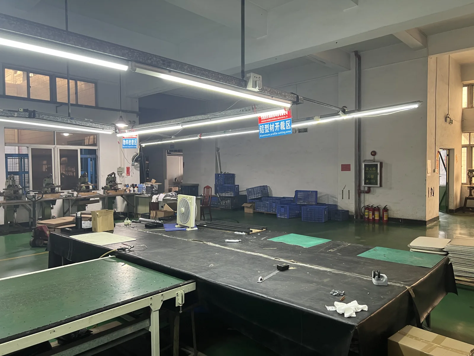 Cutting area with long dark work benches, blue crates stacked along the wall and machines behind