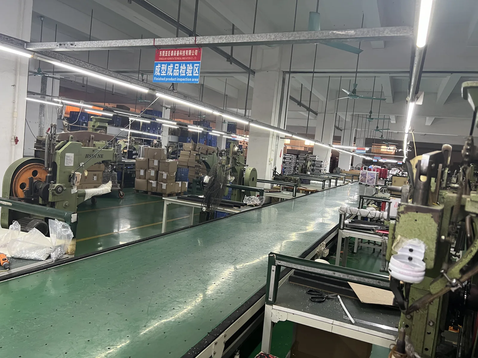 Finished product inspection area with a long green conveyor and machines along one side
