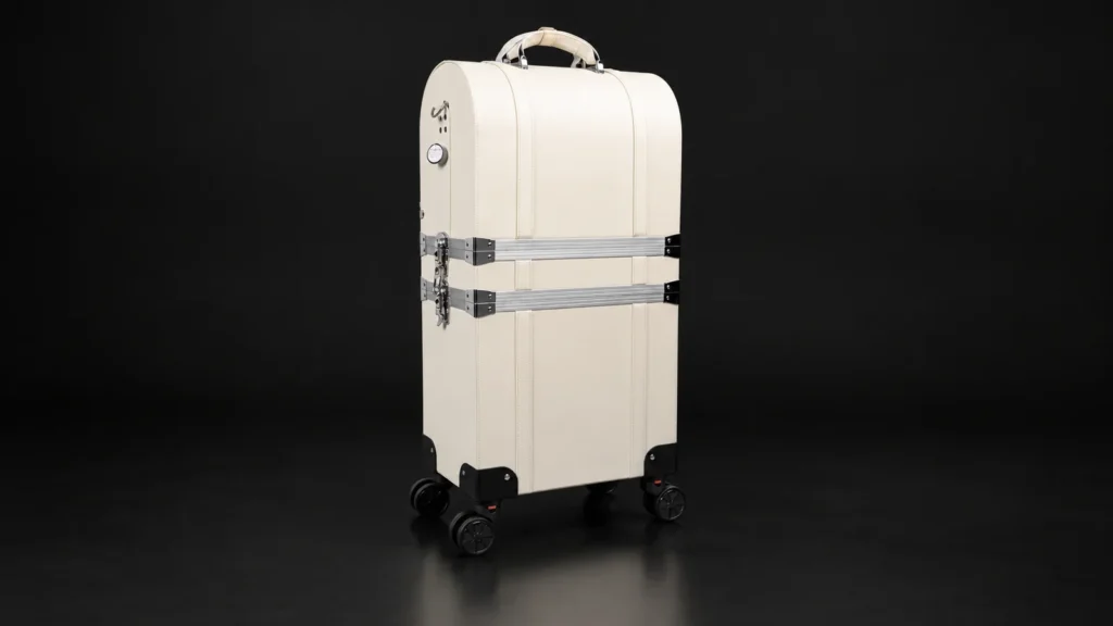Cream two-tier makeup trolley case with aluminum straps from the Aluvox factory, studio shot on black