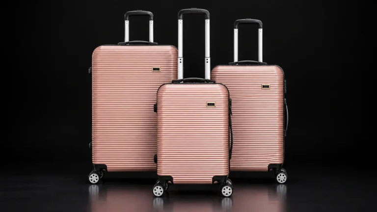 Three sizes of a rose gold hardside suitcase from the Aluvox range, studio shot on black