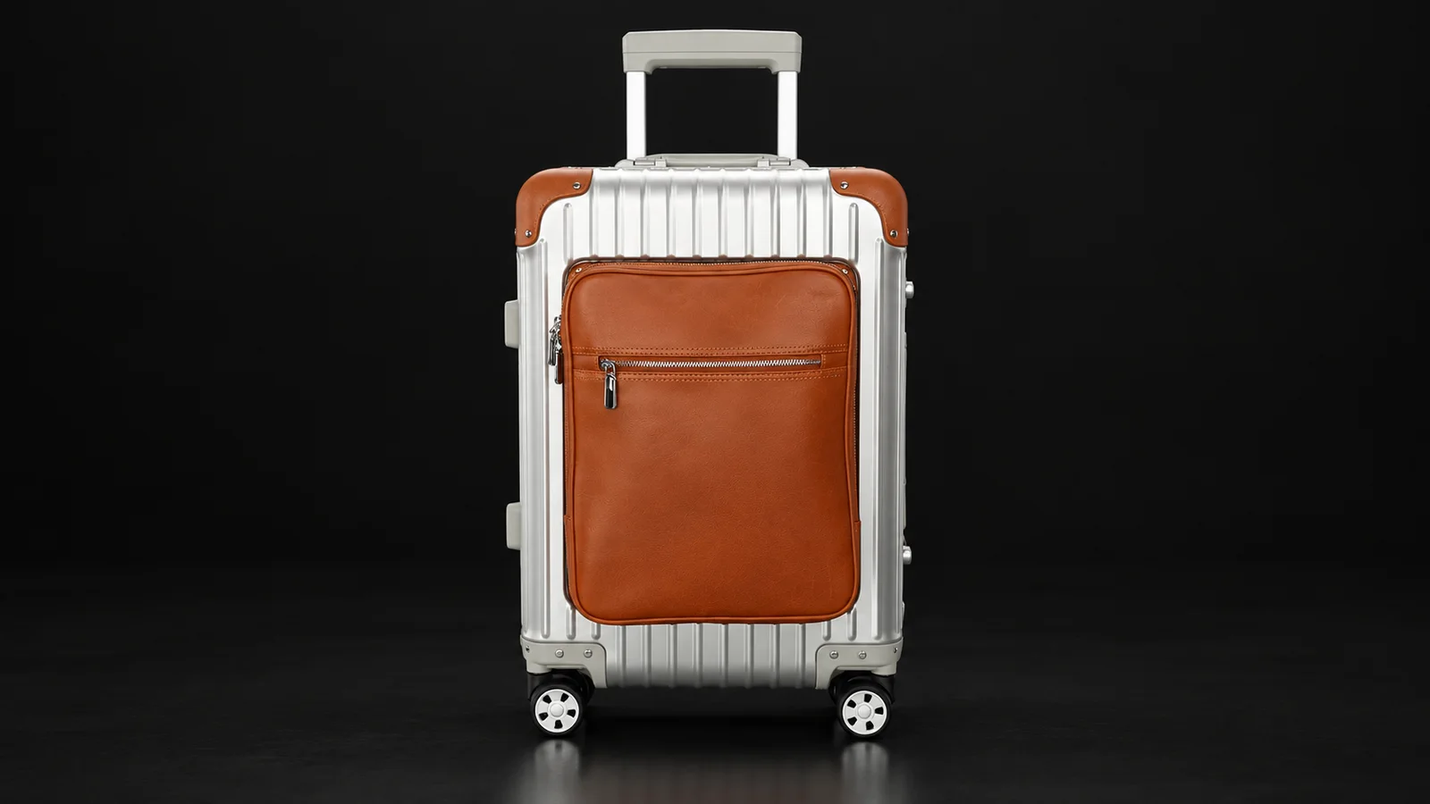 Silver ribbed aluminum suitcase with brown leather front pocket from the Aluvox factory, studio shot on black