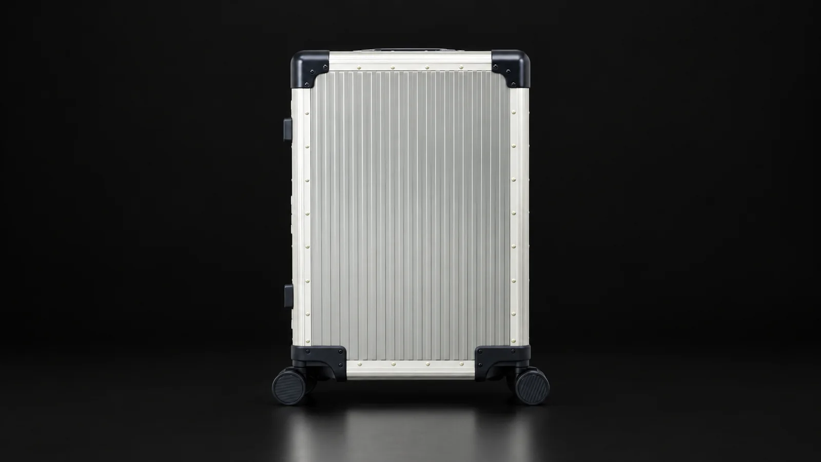 Brushed titanium suitcase with dark corner guards from the Aluvox factory, studio shot on black