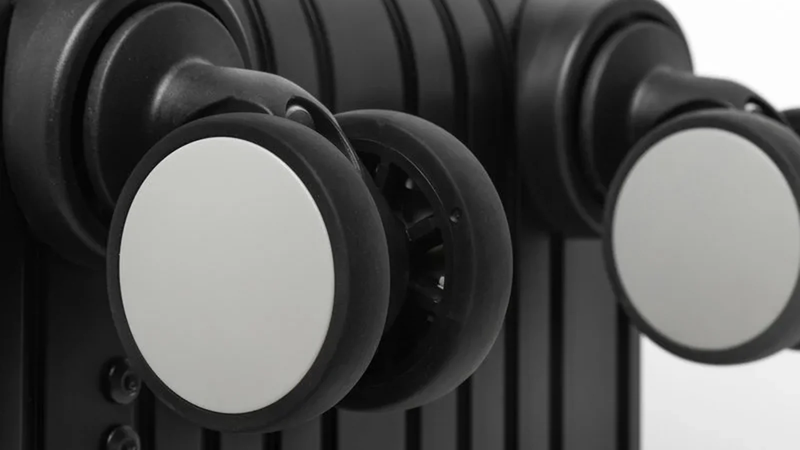 Double spinner wheels and their housings on the base of a black ribbed suitcase